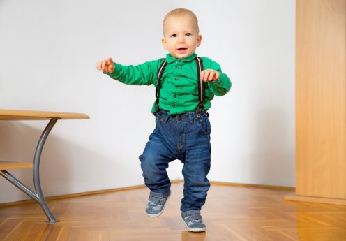 Toddler wearing suspenders learning to walk