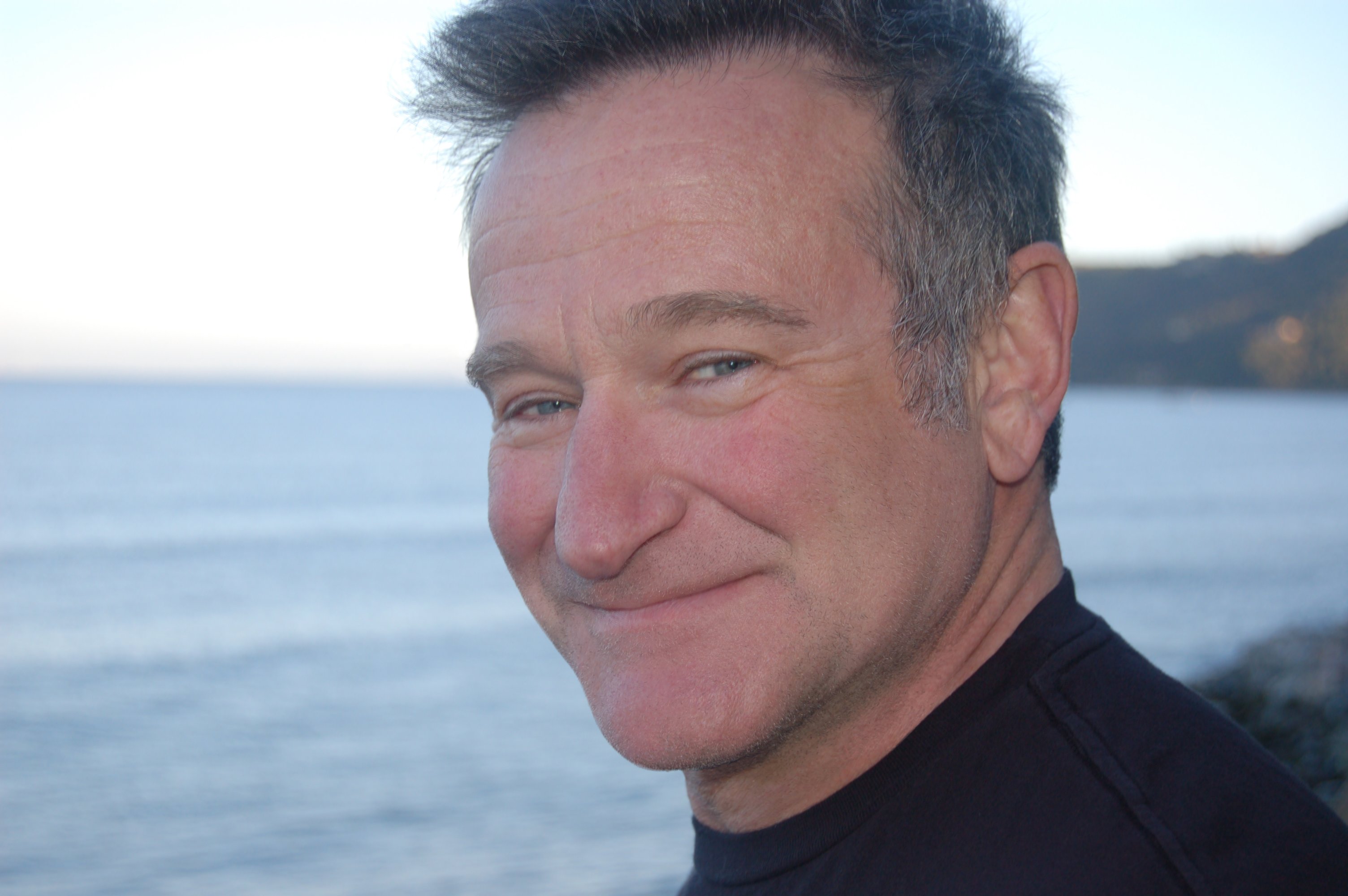 Closeup of Robin Williams smiling with beach in background