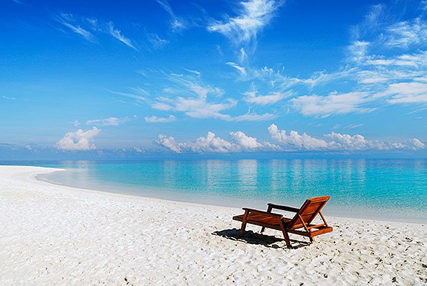 Lone beach chair sits on white sand