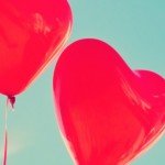 Two red heart shaped balloons with sky background