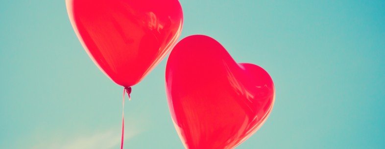 Two red heart shaped balloons with sky background
