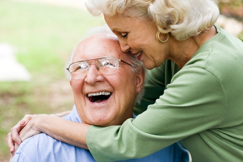 An eldery couple embrace in a hug with big smiles