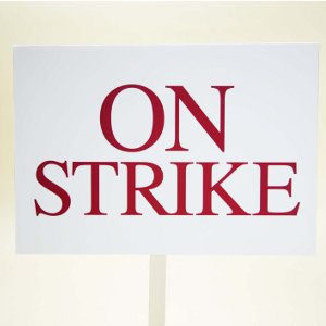 White picket sign reads On Strike in red lettering