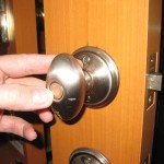 Hand reaches out to open wooden door with silver doorknob