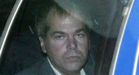 John Hinckley in the back of a cop car with angry expression