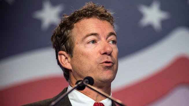 Rand Paul mid-sentence at speaking convention with American flag in background