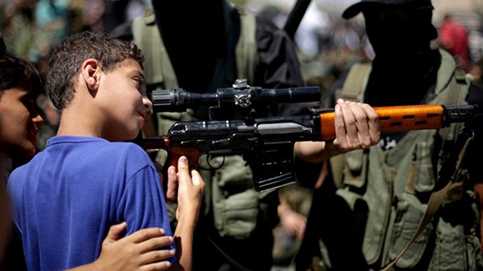 Young boy is shown how to hold rifle