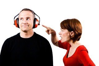 Woman points at man's face as man listens to headphones