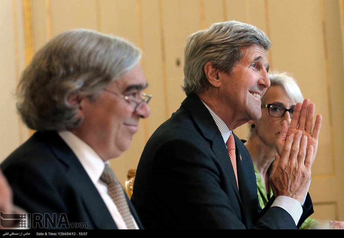 John Kerry smiles and claps at a conference