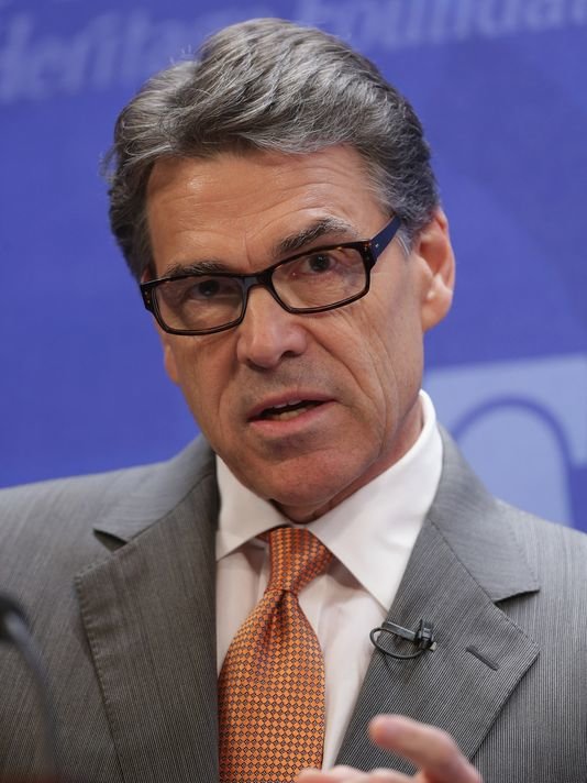 Rick Perry wearing glasses and orange tie during interview