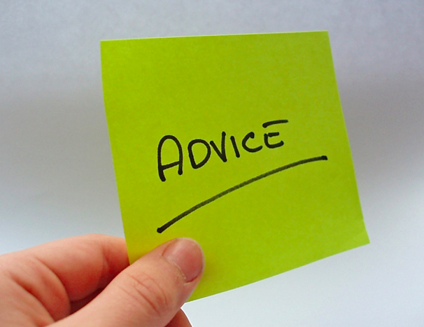 A hand holds green post it note with the word Advice underlined