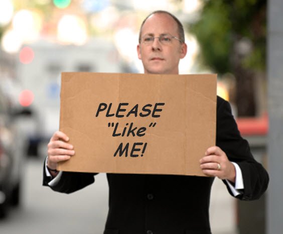 Man in suit holds cardboard sign that reads Please Like Me!