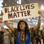 Woman holds sign in street reading Black Lives Matter
