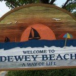 Welcome to Dewey Beach sign with sailboats and an umbrella