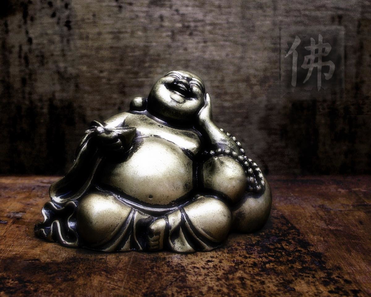A laughing Buddha statue sitting on wooden table