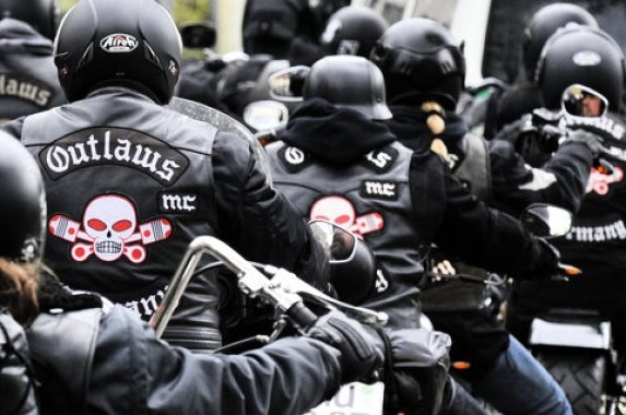 Several motocycle bikers wearing black Outlaws jackets