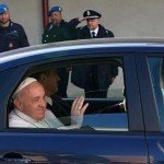 Pope Francis riding in backseat of car as bystanders salute