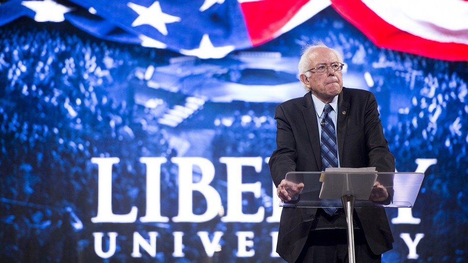 Sanders standing at podium with Libery University logo behind him