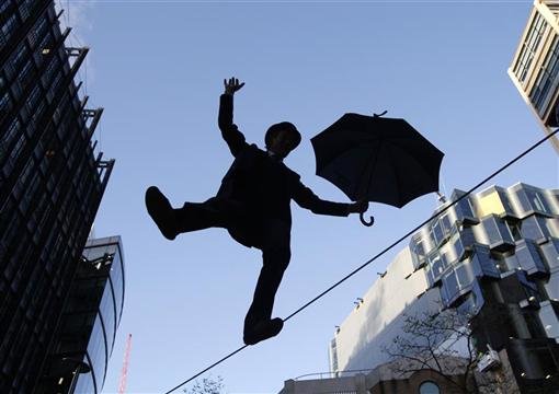 Man wearing tophat with umbrella walks on tightrope